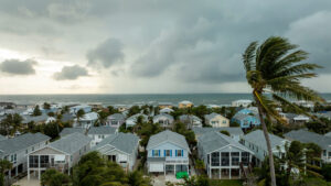 Coastal Bay County neighborhood with palms bending under an approaching hurricane sky.